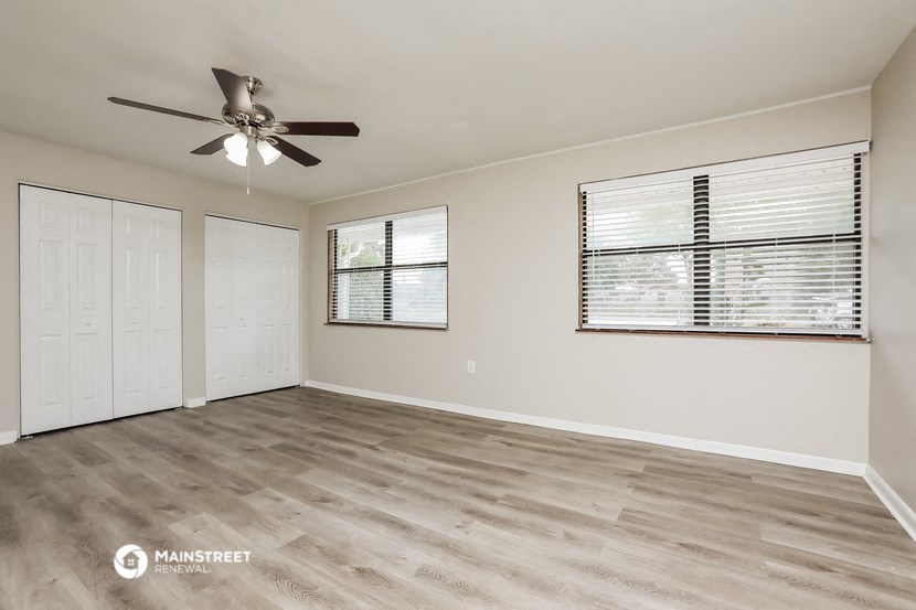 the living room is spacious and clean with a ceiling fan