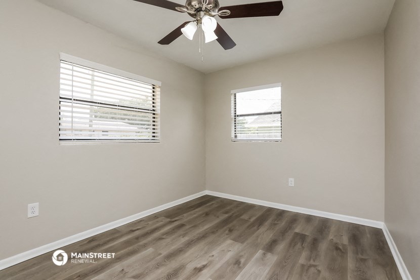 the spacious living room with wood flooring and a ceiling fan