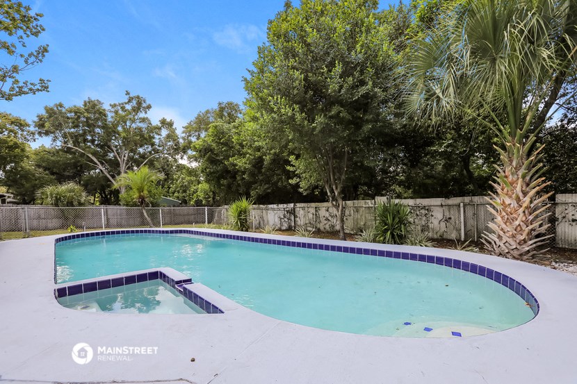 a pool and spa in a backyard with trees