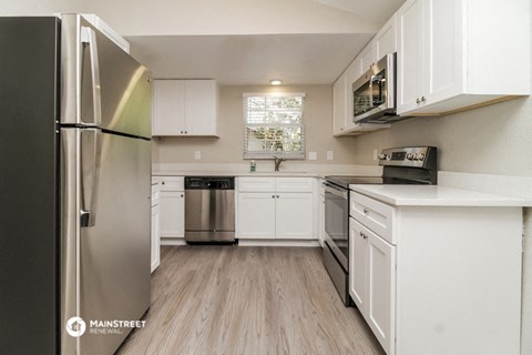a white kitchen with stainless steel appliances and white cabinets