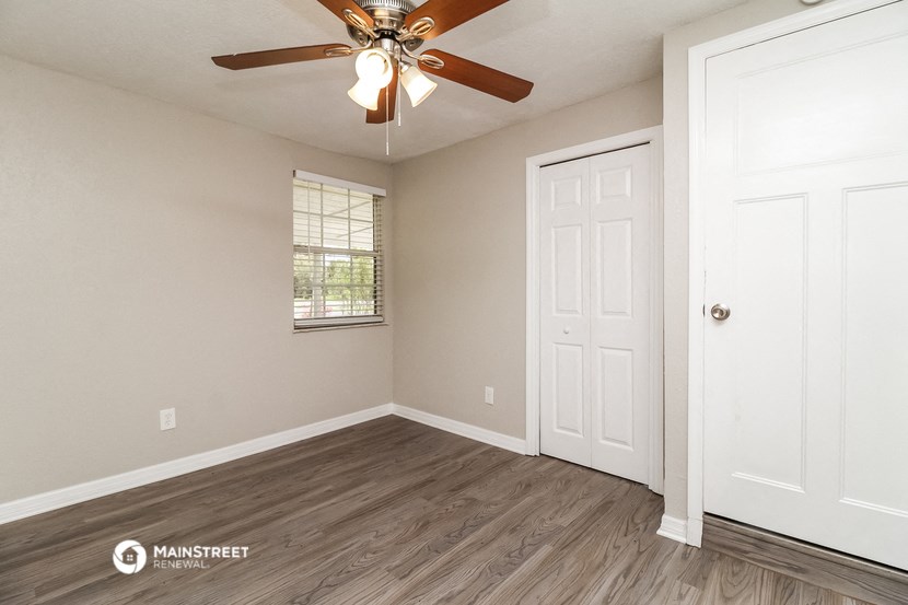 the spacious living room of a home with a ceiling fan
