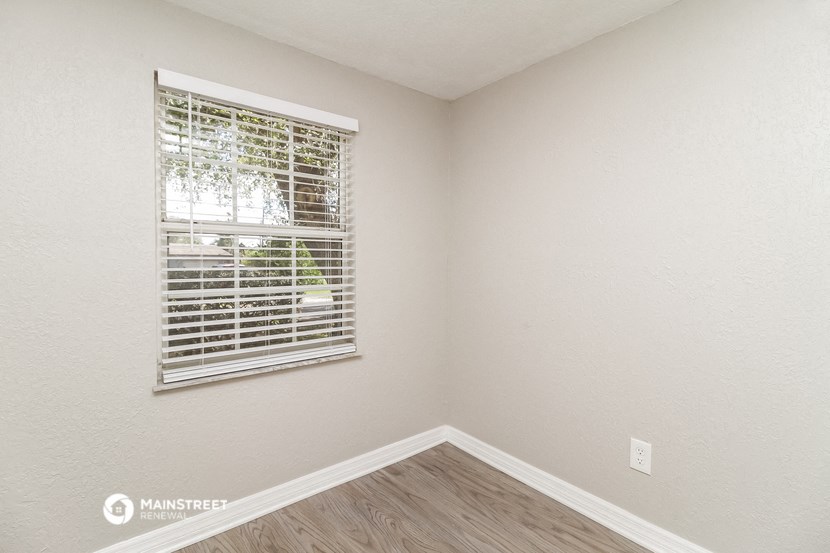 the bedroom has a window and hardwood flooring and a window