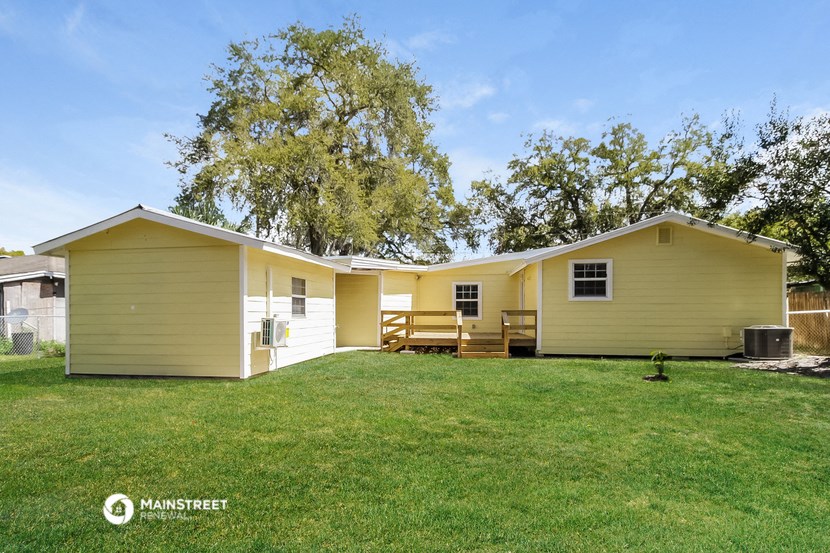 a yellow house with a green lawn and a tree