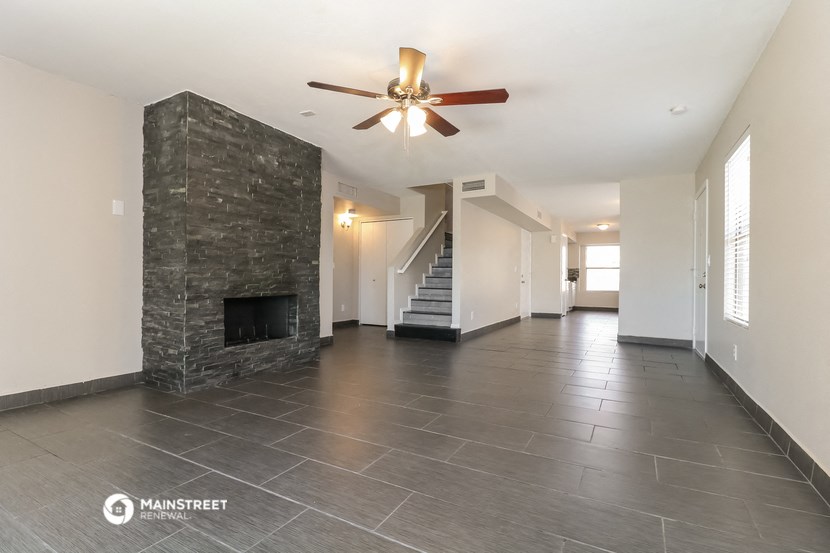 a large living room with a stone fireplace and a ceiling fan