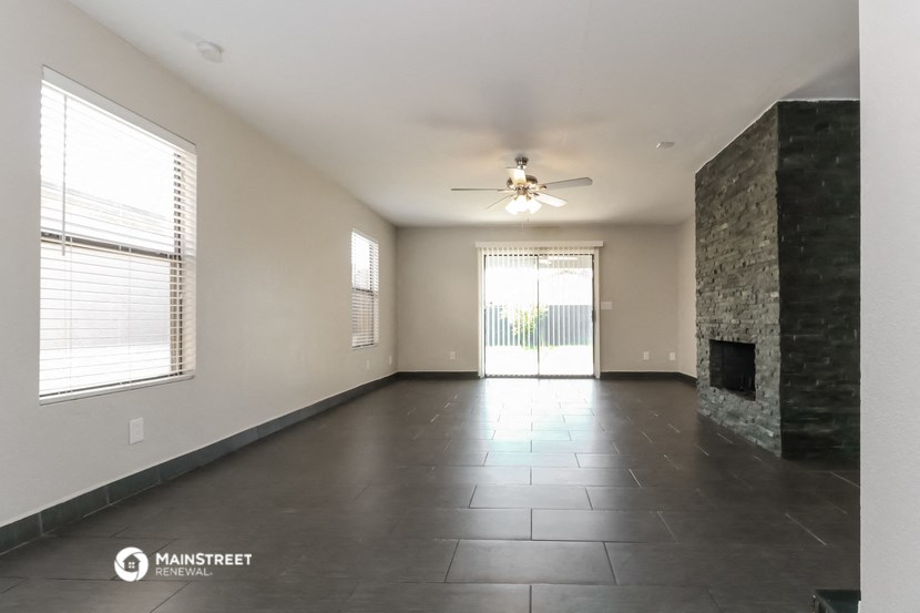an empty living room with a fireplace and a ceiling fan