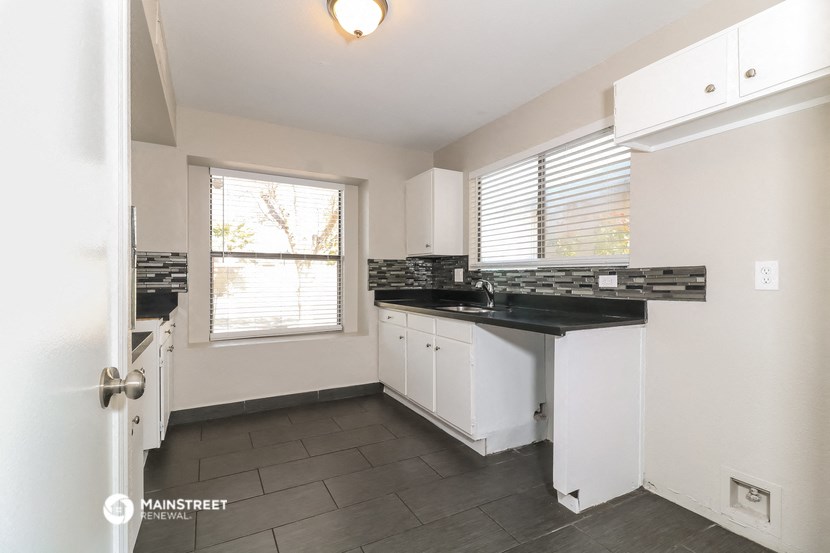 a kitchen with black countertops and white cabinets and a window