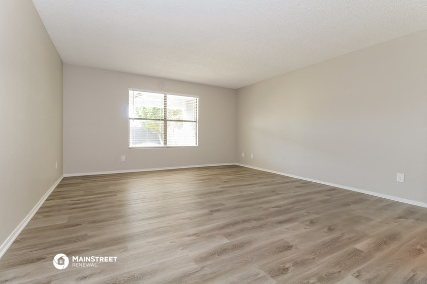 the spacious living room with wood flooring and a window