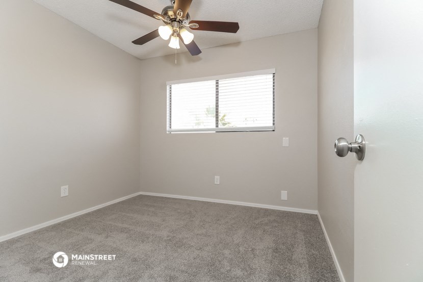 an empty room with a ceiling fan and a window