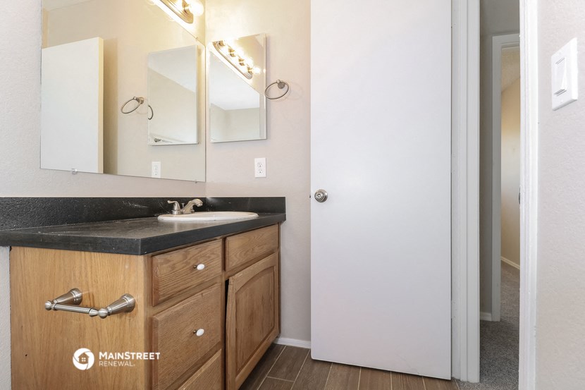a bathroom with a sink and mirror and a door to a closet
