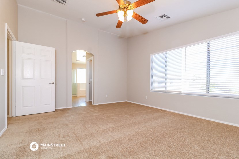 an empty living room with a ceiling fan and a large window