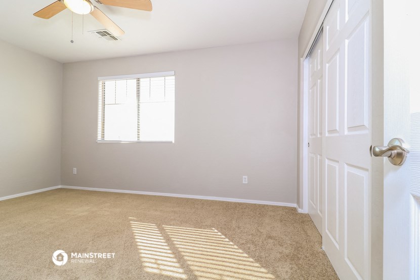 an empty room with a ceiling fan and a window