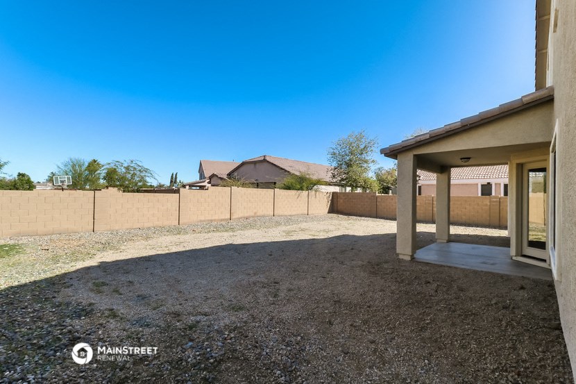 an empty yard with a fence and a house in the background
