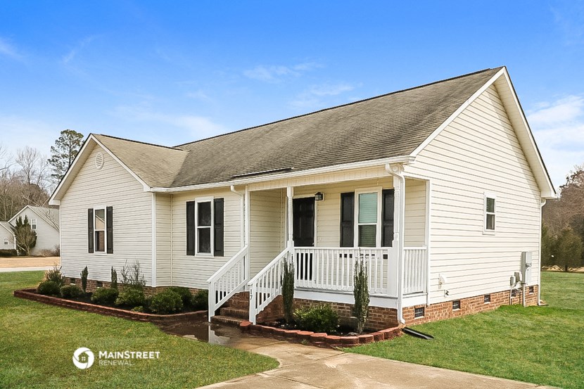 the front of a white house with a porch and a lawn