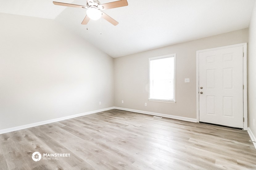 the spacious living room with wood floors and a ceiling fan