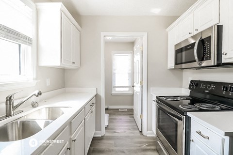 a kitchen with white cabinets and black appliances