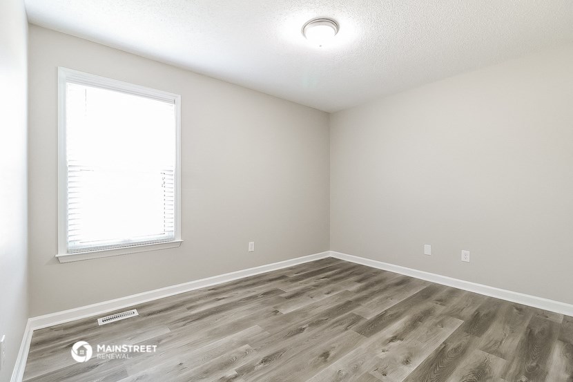 an empty room with wood flooring and a window