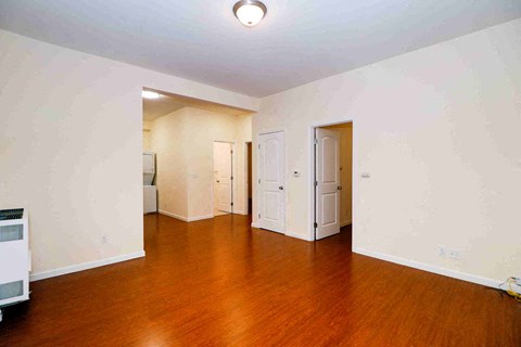 an empty living room with wood floors and white walls