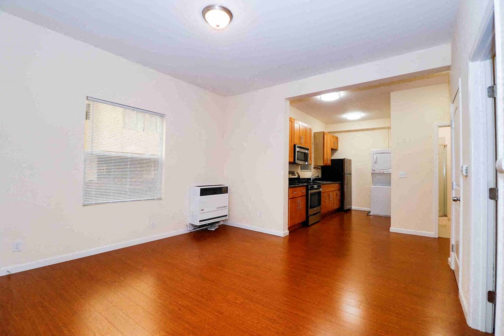 an empty living room and kitchen with wood floors and a heater