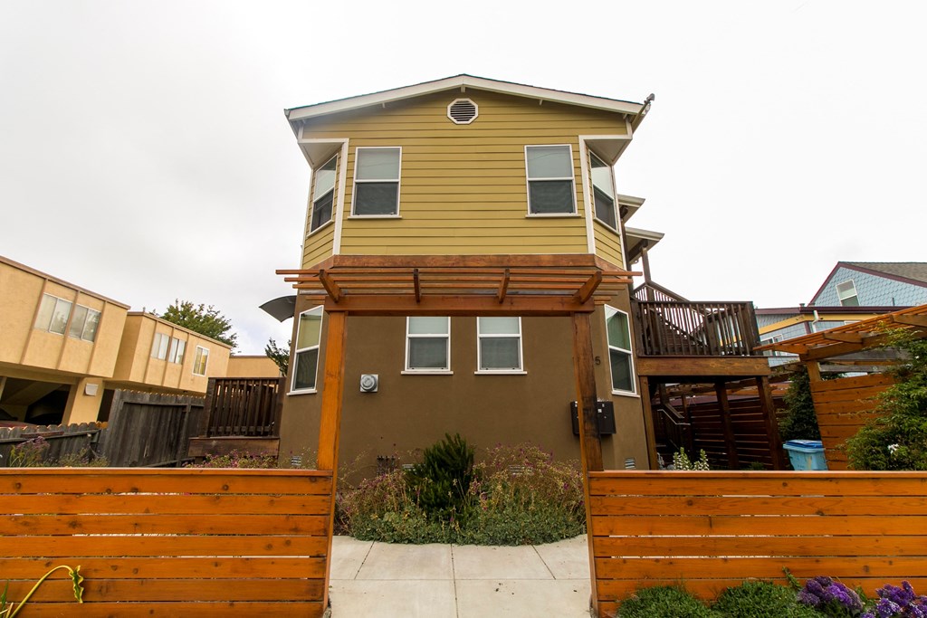 a tall yellow house with a wooden fence in front of it