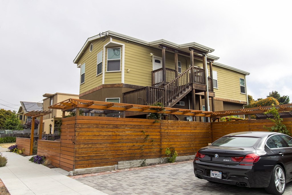 a car parked in front of a house with a wooden fence