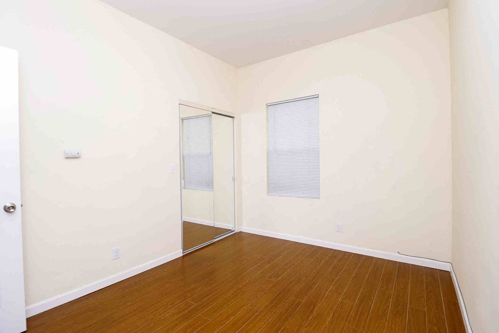 a bedroom with a wood floor and white walls and a closet