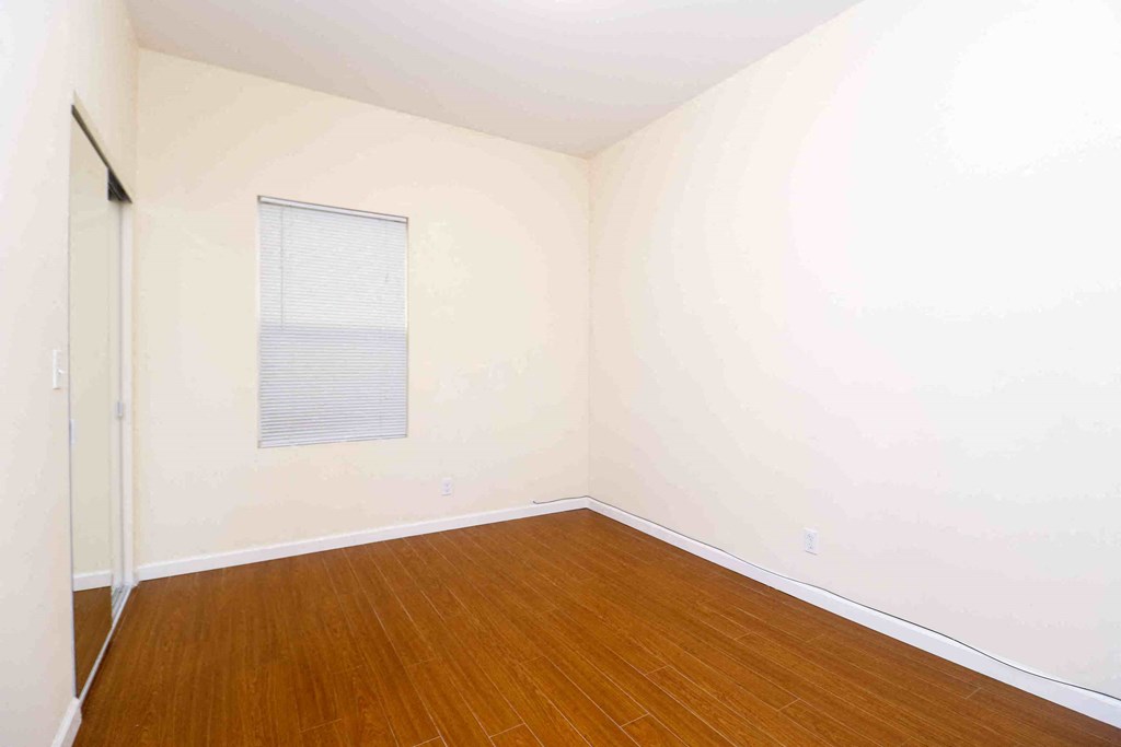 an empty room with wooden floors and a window