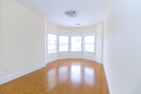 an empty room with white walls and a wood floor and a window
