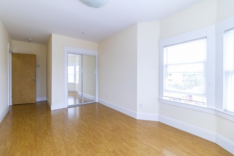 an empty living room with wood floors and white walls