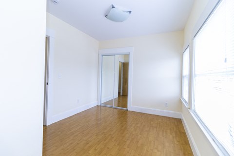 an empty living room with white walls and a wooden floor