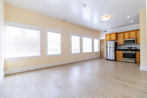 the living room of an empty apartment with a wood floor and large windows