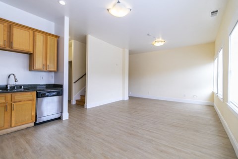 an empty kitchen and living room with wood floors and white walls