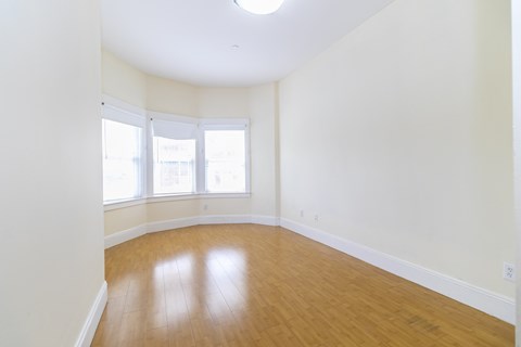 an empty living room with wood floors and white walls