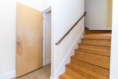 a staircase with wooden floors and a wooden door next to a white wall