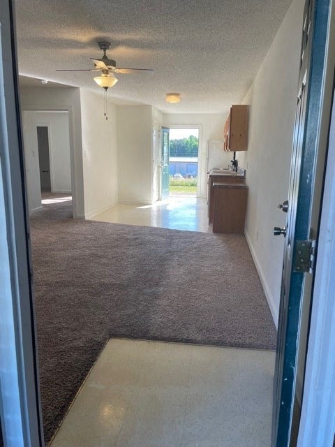 A room with a ceiling fan and a brown carpet.