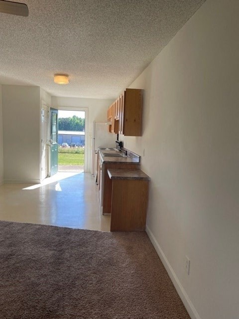 A long hallway with a brown carpet and a wooden cabinet.