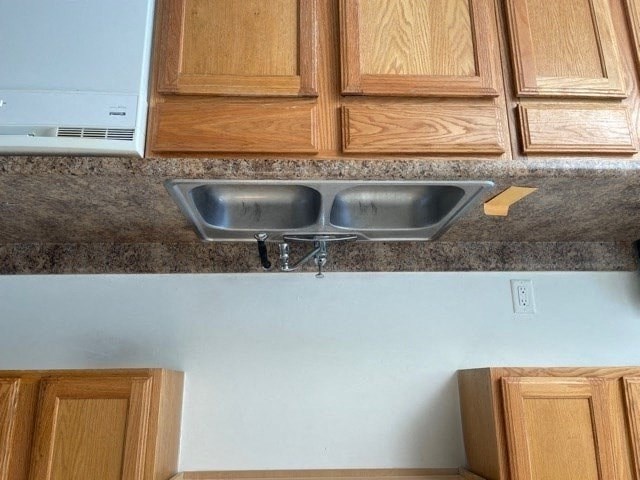 A kitchen with wooden cabinets and a double sink.