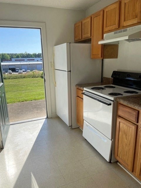 A kitchen with white appliances and wooden cabinets.