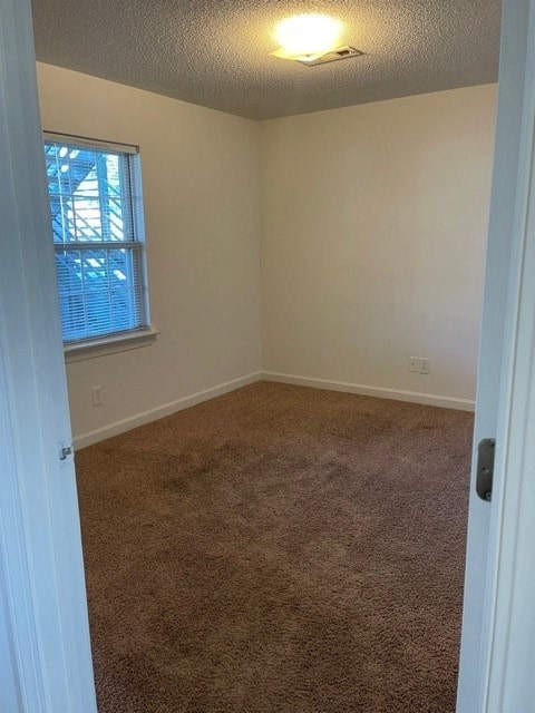 A room with a carpeted floor and a window with blinds.