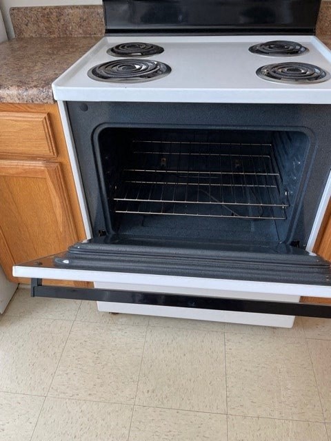 A white oven with four burners is on a kitchen counter.