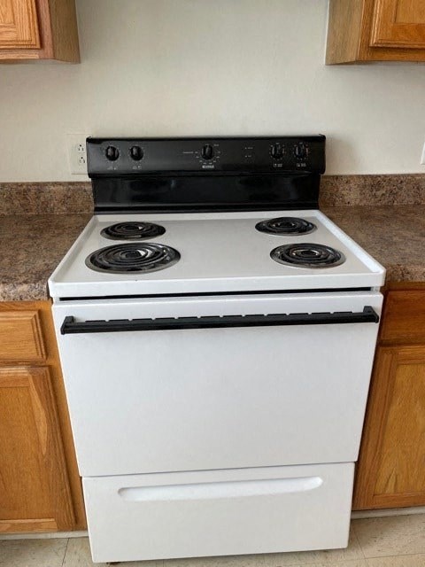 A white stove with a black top is in a kitchen.