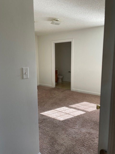 A room with a carpeted floor and a doorway leading to another room.