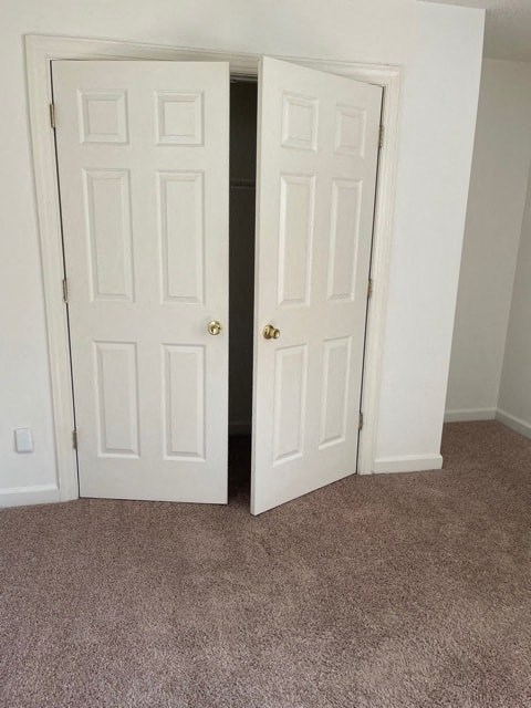 Two white doors in a room with carpeted floor.