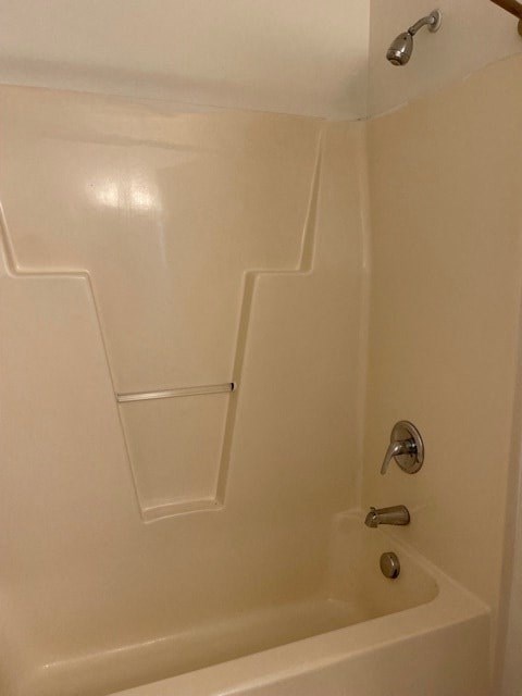 A white bathtub with a silver faucet and a silver shower head.