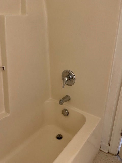 A white bathtub with a shower head and faucet.