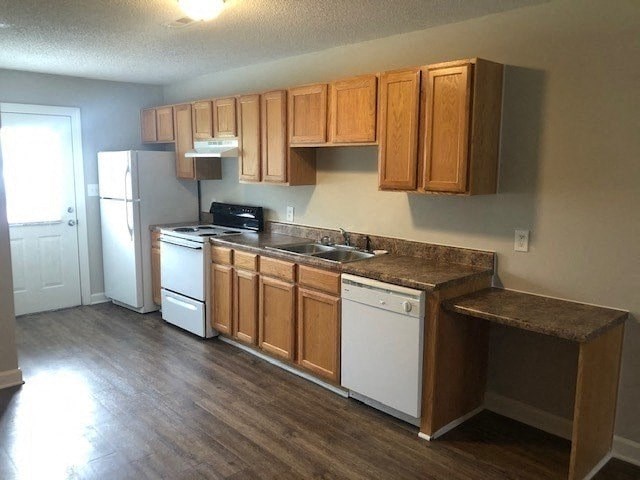 A kitchen with wooden cabinets and white appliances.