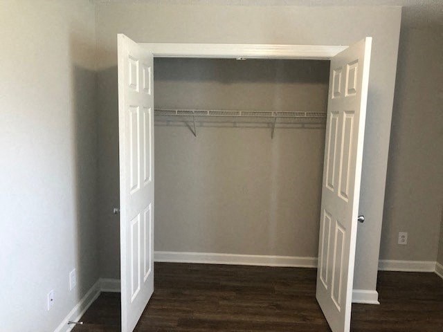 A white door is open to a room with a grey wall and a wooden floor.