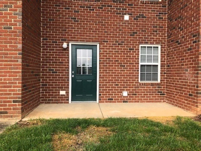 A brick house with a green door and a window.