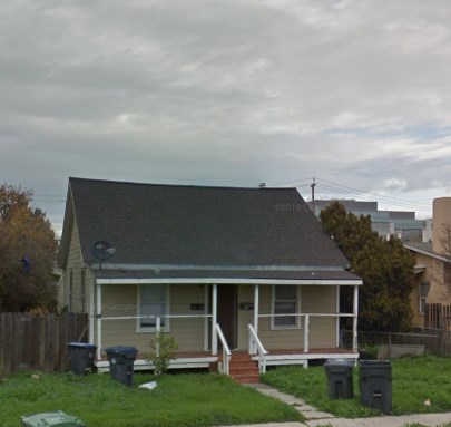 A house with a grey roof and a beige wall with a small porch.