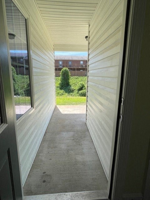 A view from the inside of a house looking out to a green lawn and a building in the distance.
