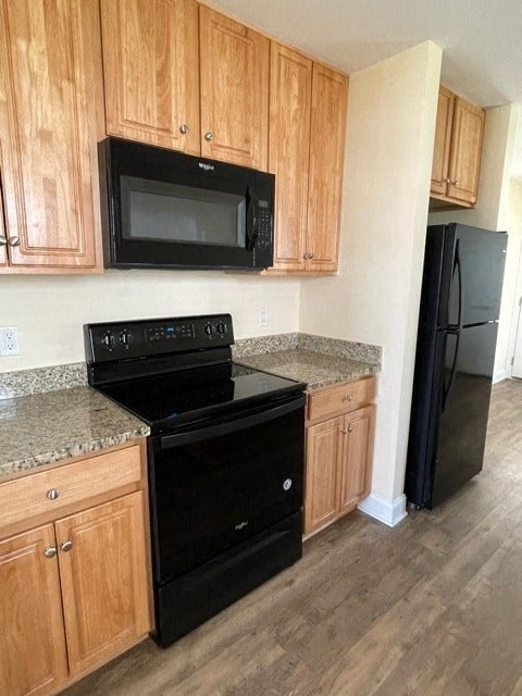 A kitchen with wooden cabinets and black appliances.